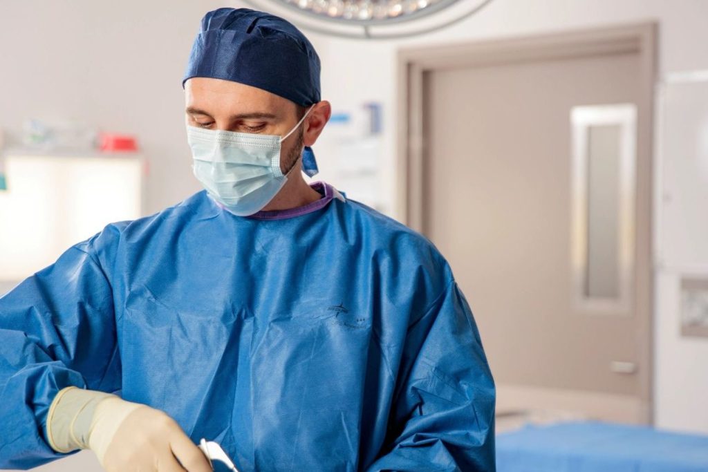 Dr Alexey Borshch, gowned and masked, performing orthopaedic surgery
